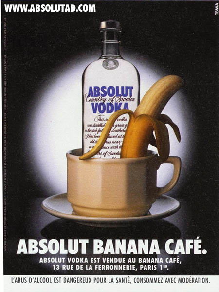 Bottle with a coffee cup in front of it that has a banana in it.